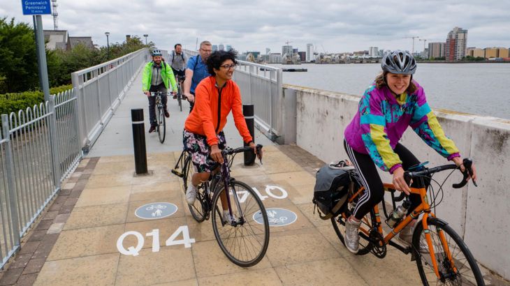People on bikes cycling over bridge in London