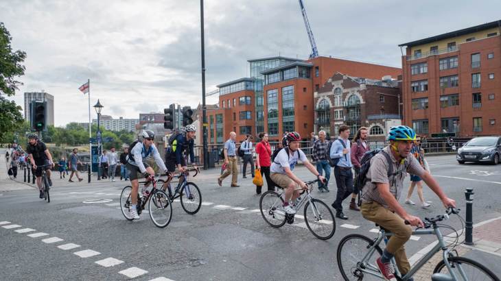 people walking and on bikes using a road crossing in a city
