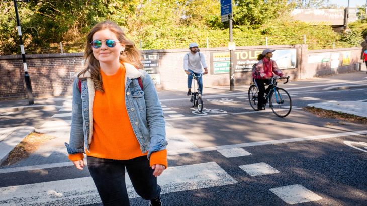 Woman walking on city street with people cycling in background