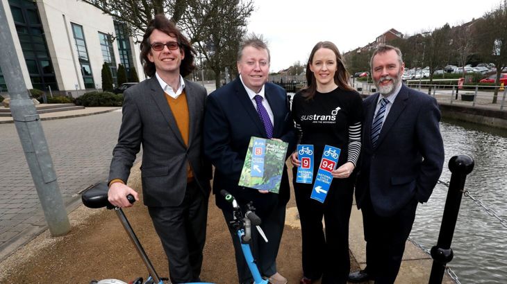 Walk Wheel Cycle Trust CEO Xavier Brice standing with three other people, holding a Paths for Everyone report and National Cycle Network signs