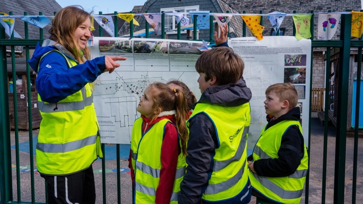 Walk Wheel Cycle Trust project officer looking at a school street plan with children