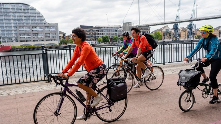 A group of people cycling along the river Thames in London 
