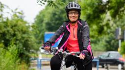 Lady stood with her bicycle wearing a helmet