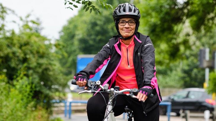 Lady stood with her bicycle wearing a helmet