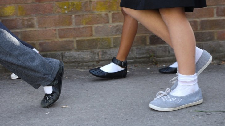 A close up photo of the legs of some school children walking to school