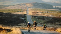 Three cyclists on road through Scottish countryside