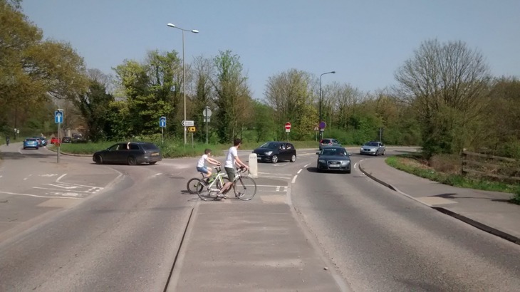 cyclists waiting to cross road at busy junction