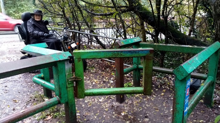 A person on a mobility scooter next to a metal gate