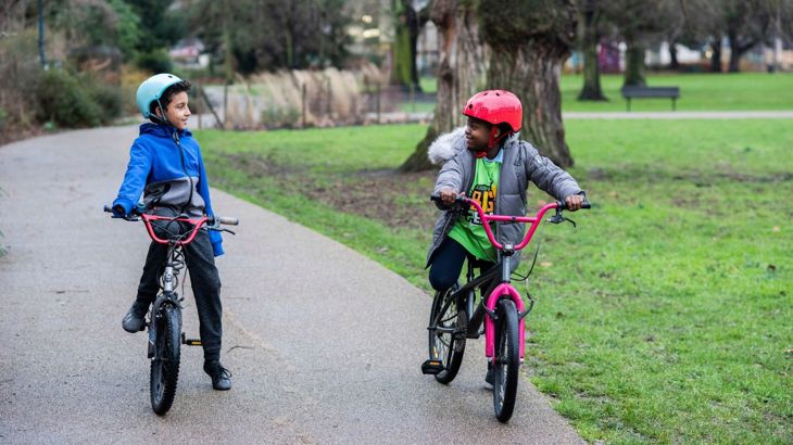 two young children on their bikes with helmets on a traffic-free path