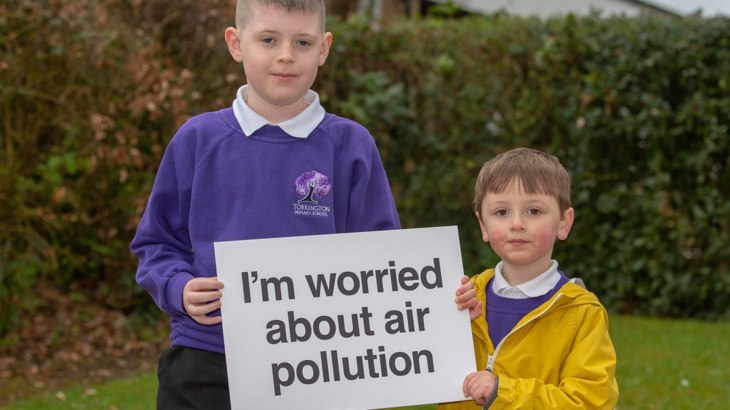 Two school boys holding sign about air pollution
