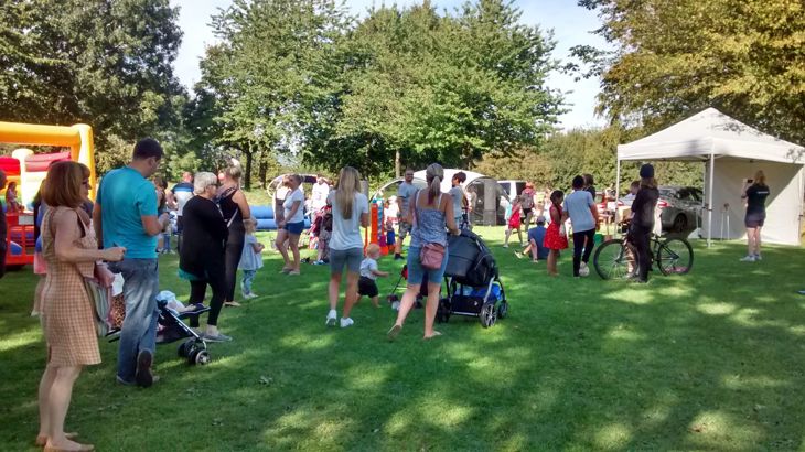 Families milling about in park with tents and bouncy castle