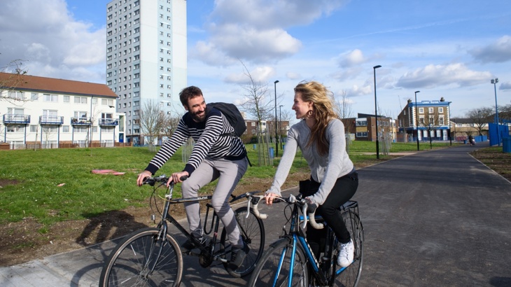 Two colleagues cycling along a path side-by-side when commuting to work
