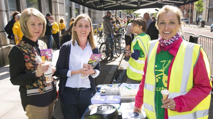 staff member dianne at an information stand with two women holding cycling literature at cycle to work day event outside in Belfast City Centre