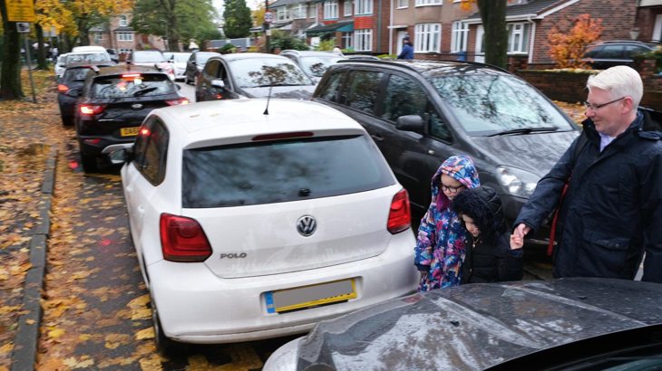 Family walking across a gridlocked road outside the school gates
