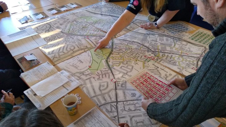 People looking at and point to a big map on a table
