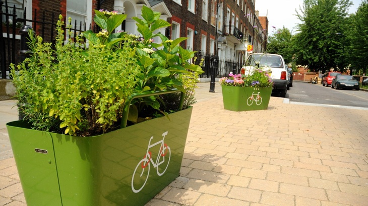 Two planters with flowers and plants on a traffic-free space in a residential street