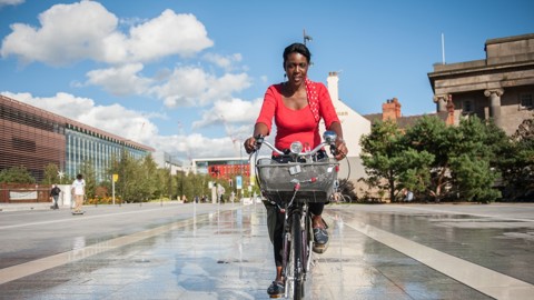 A women cycles through birmingham on a warm sunny day 