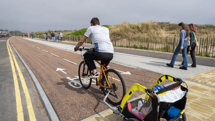 Male Cyclist With Child In Trailer On Cycle Path
