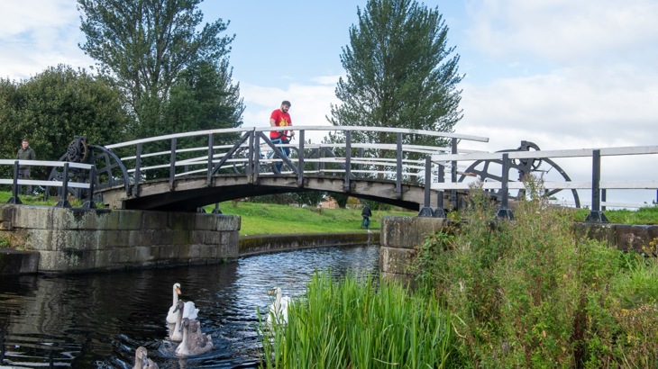 Man Crossing A Bridge Over A Canal 