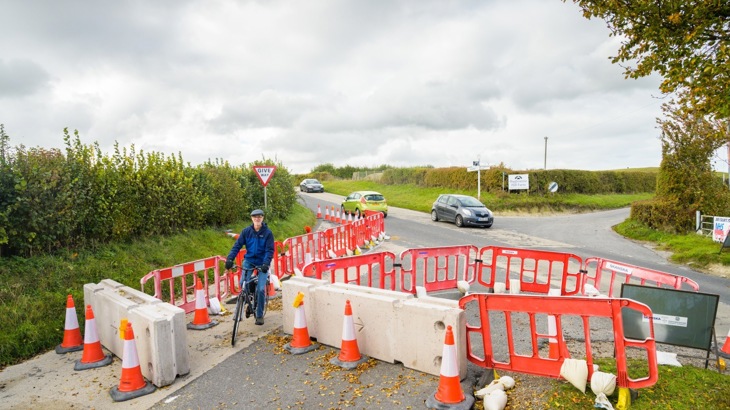 Man cycling through temporary barriers that prevent cars from using the road