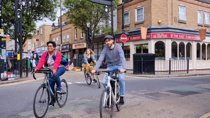 A lady and a man cycle casually through a London borough