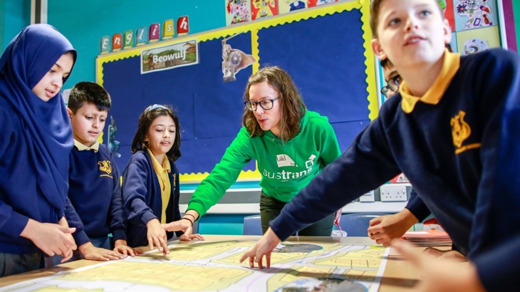 A Walk Wheel Cycle Trust member of staff talks with children at a street design workshop at Acasias Primary School 