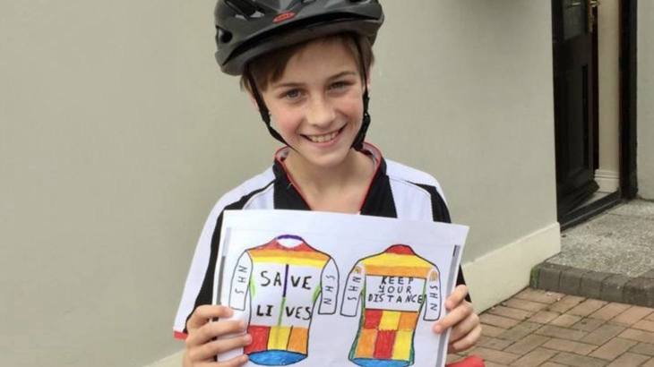 Conan Shivers from St Mary's Primary School holding his cycling jersey design that has saves lives on the front and keep your distance on the back and NHS on the sleeves